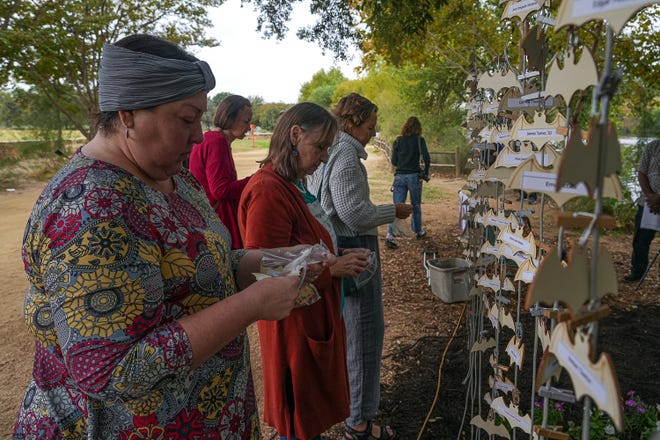 Blythe Plunkett, president of House the Homeless, hangs wood bats labeled with the names of deceased homeless poeple at a memorial service at Auditorium Shores on Sunday, Nov. 17, 2024 in Austin. Advocates and members of the homeless community gathered to honor the more than 200 homeless people that died between September of 2023 and November of 2024.