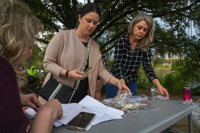 Laura Evanoff, left, and Kelli Brizendine, right, pick up bags of names of deceased homeless people at a memorial service at Auditorium Shores on Sunday, Nov. 17, 2024 in Austin. Advocates and members of the homeless community gathered to honor the more than 200 homeless people that died between September of 2023 and November of 2024.