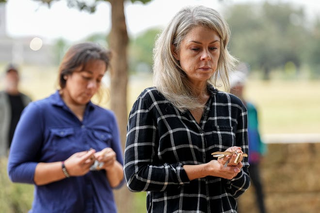 Kelli Brezendine waits in line to hangs a wood bat with the name of a deceased homeless person at a memorial service at Auditorium Shores on Sunday, Nov. 17, 2024 in Austin. Advocates and members of the homeless community gathered to honor the more than 200 homeless people that died between September of 2023 and November of 2024.