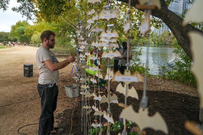 Andrew Willard hangs small wood bats with the names of deceased homless people at a memorial service at Auditorium Shores on Sunday, Nov. 17, 2024 in Austin. Advocates and members of the homeless community gathered to honor the more than 200 homeless people that died between September of 2023 and November of 2024.