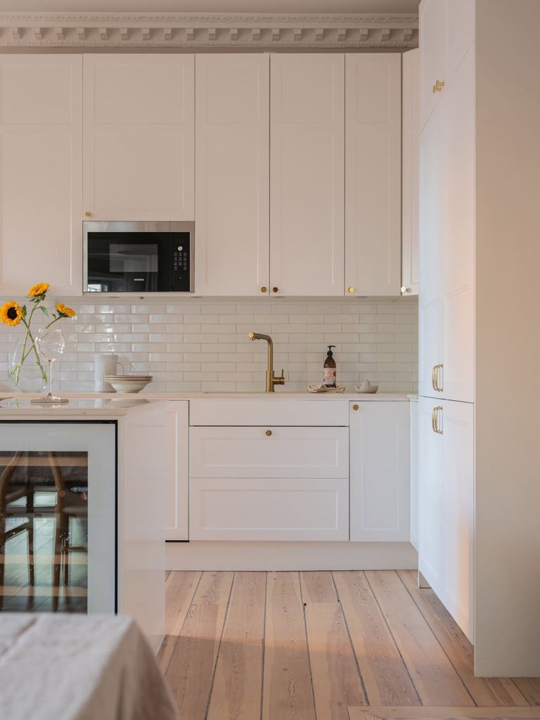 A white shaker kitchen with gold hardware and a white subway tile backsplash