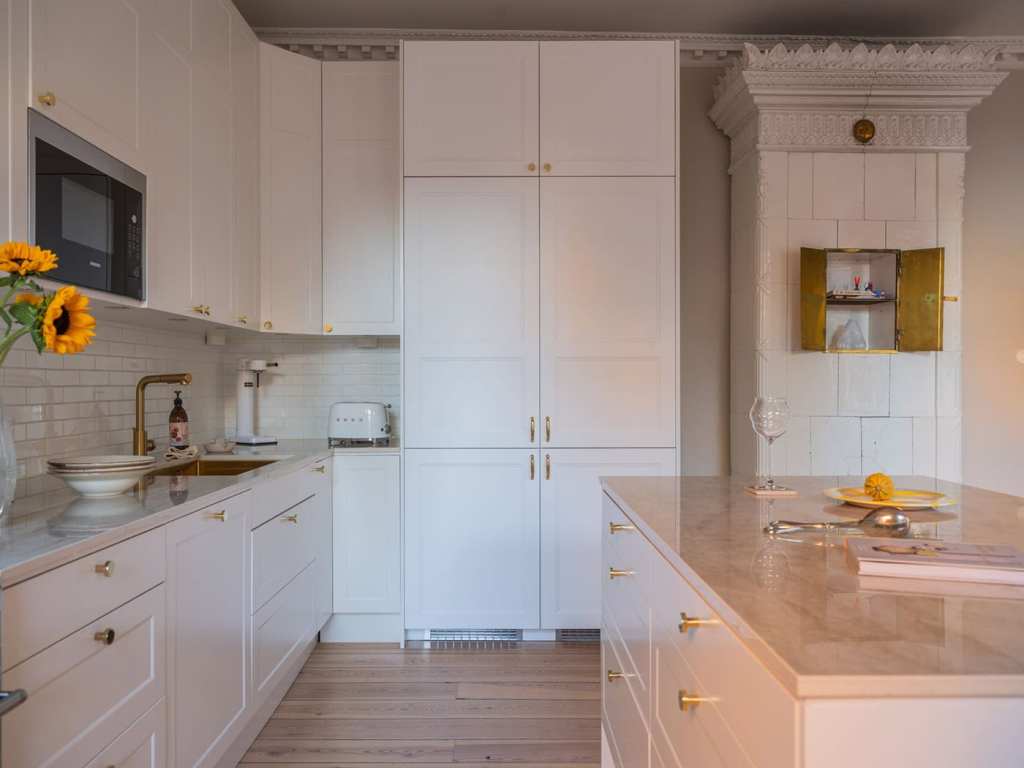 A white shaker kitchen with gold hardware and a white subway tile backsplash