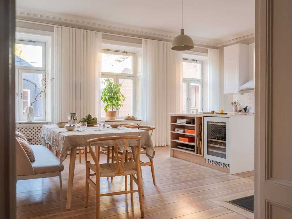 A white shaker kitchen with a spacious dining area in front of the window