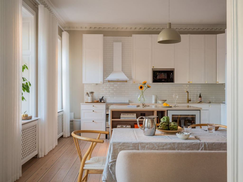 A white shaker kitchen with gold hardware and a white subway tile backsplash