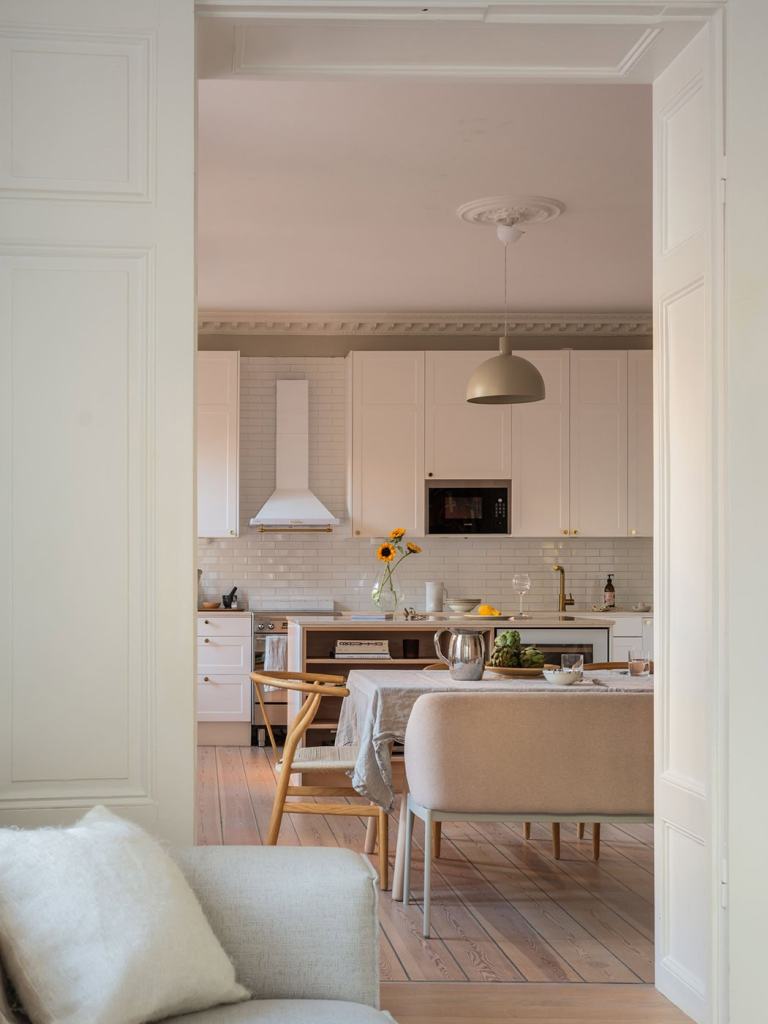 A white shaker kitchen with a spacious dining area in front of the window