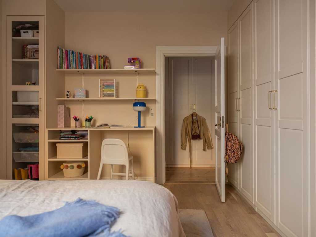 A warm beige kids room with a custom DIY desk with storage