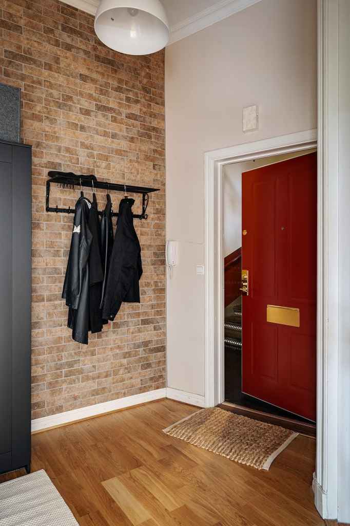 A small entryway with a fake brick wall and a black wardrobe