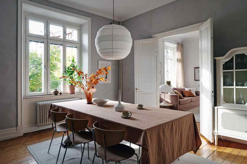 A dining room with grey limewash walls and a warm palette in the accessories and furniture