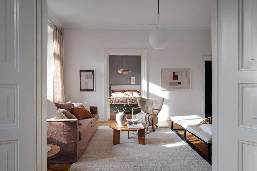 A living room with white walls and a natural color palette, brown sofa