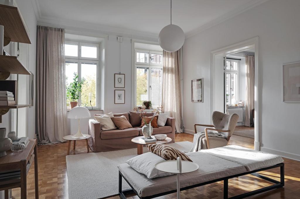 A living room with white walls and a natural color palette, brown sofa