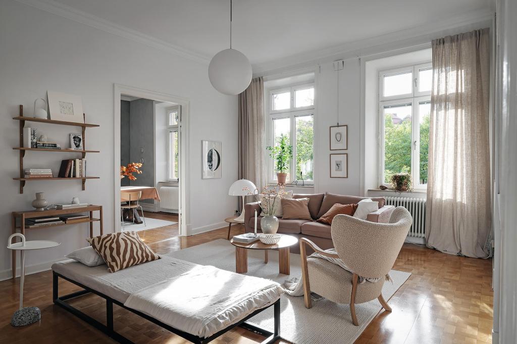 A living room with white walls and a natural color palette, brown sofa