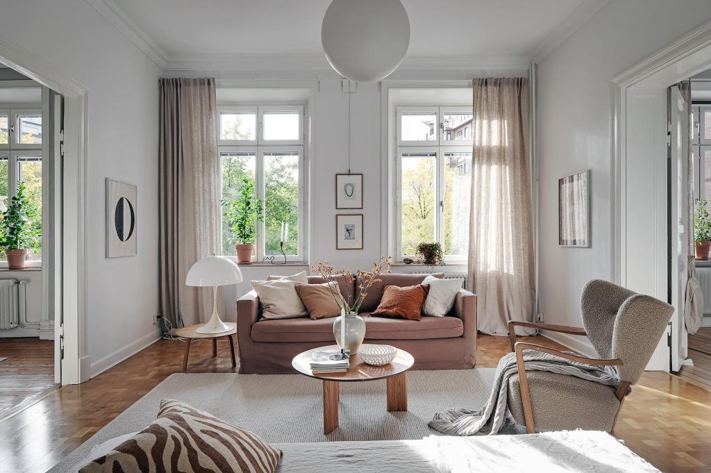 A living room with white walls and a natural color palette, brown sofa