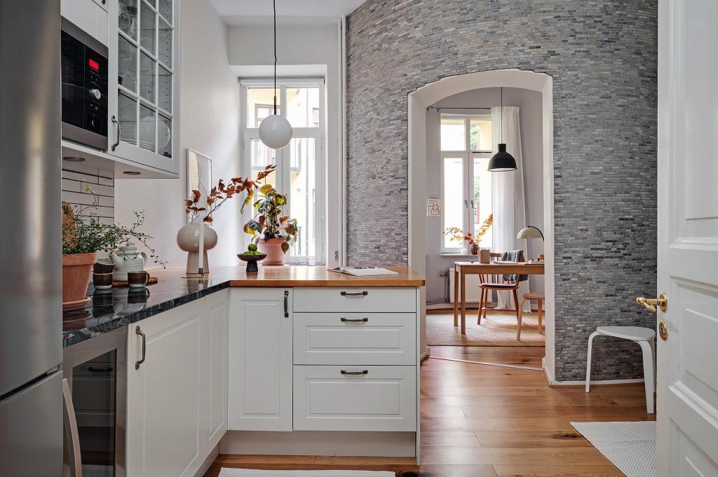 A simple white kitchen with black marble countertops and dark metal hardware