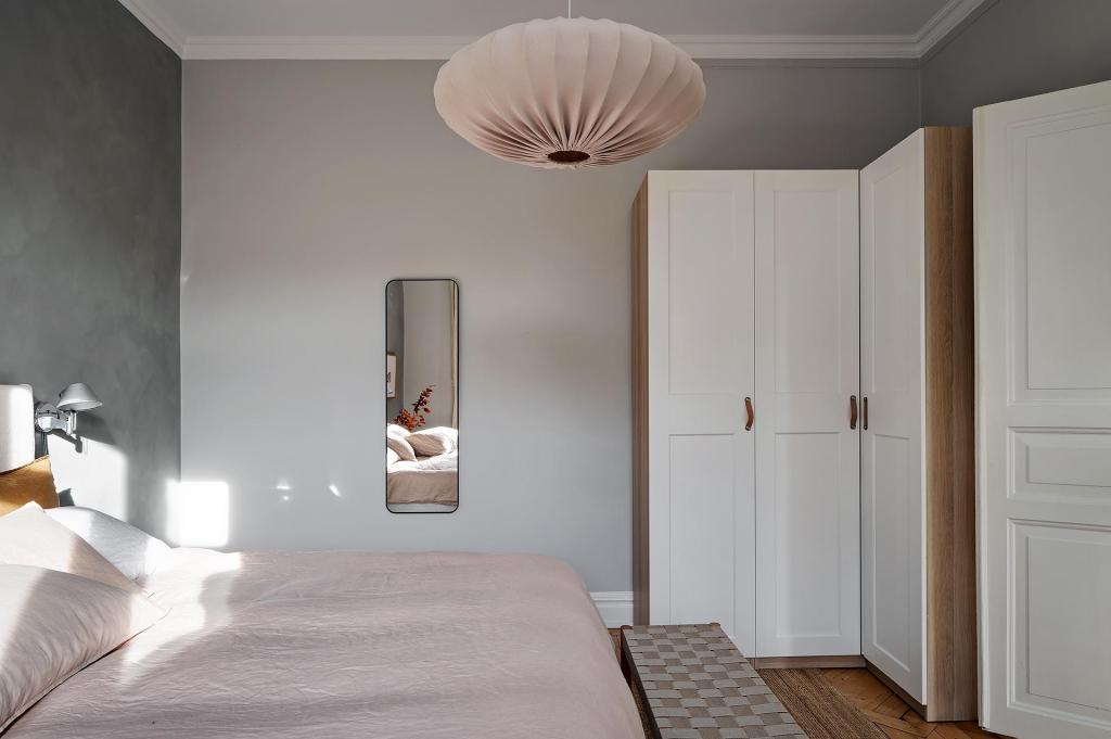 A bedroom with a grey limewash accent wall and a beige color palette in the textiles and accessories