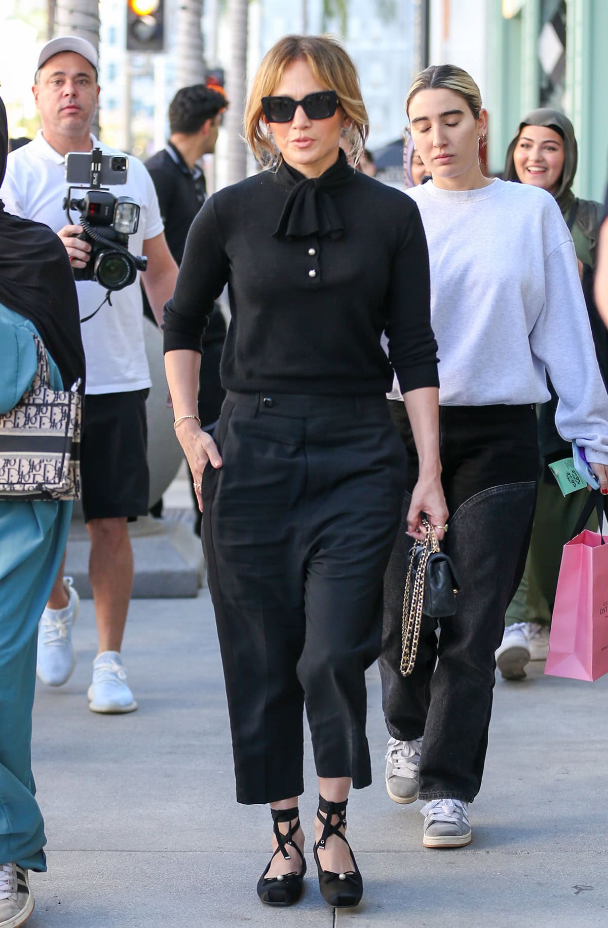 Jennifer Lopez stylishly tucks a black Dior cashmere knit sweater into a pair of black cropped trousers for her solo stroll in Los Angeles