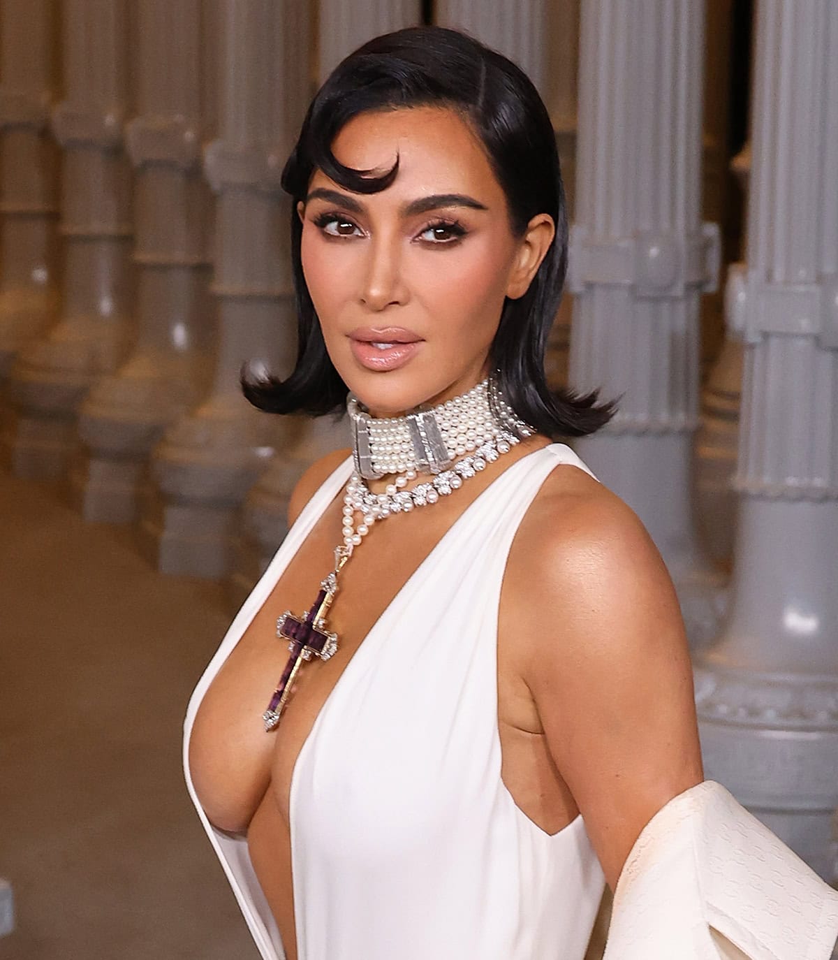 Kim Kardashian styles her hair in a sleek bob with flipped-out ends and curled fringe and wears her signature dramatic nude makeup