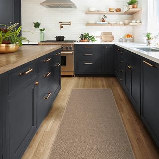 navy blue kitchen with wooden floor with jute runner showing how to make a kitchen cosy