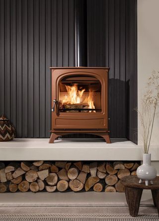 terracotta log burning stove on raised hearth with log storage