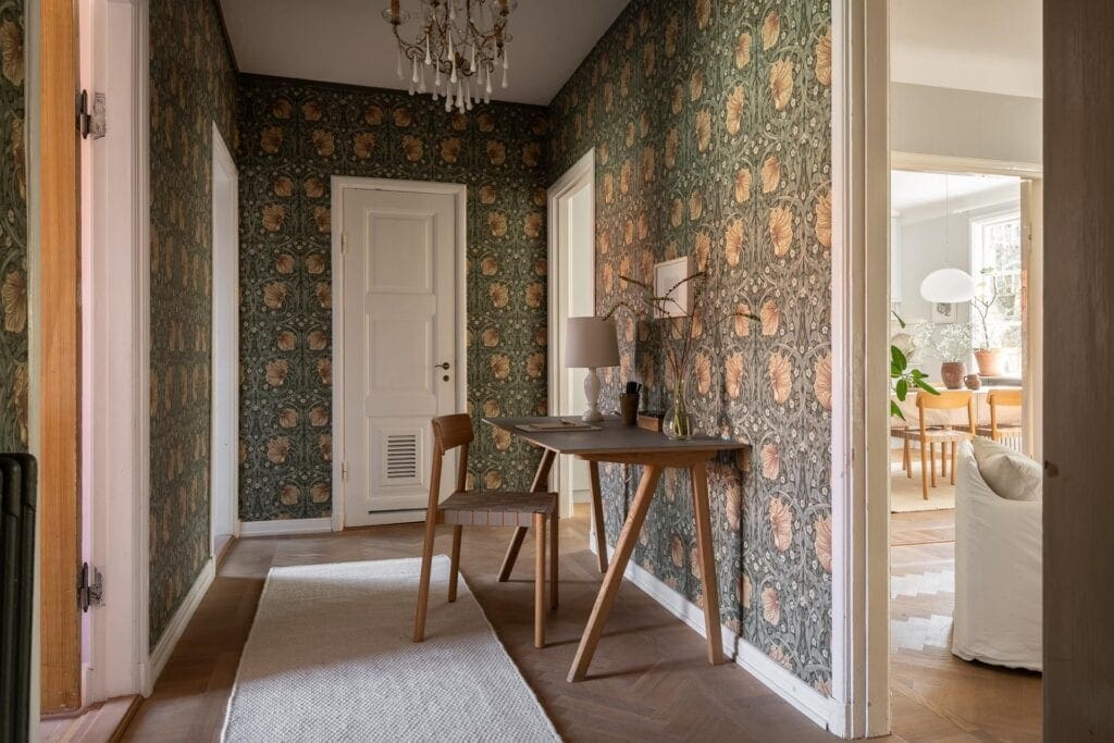 Modern-Style Wooden Desk and Chair in an Elegantly Decorated Hallway with wallpaper and a chandelier