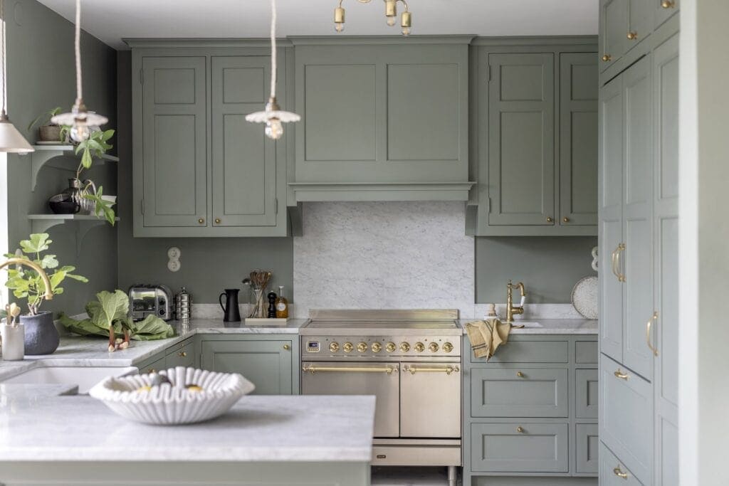 A tone-on-tone kitchen with sage green walls and cabinets, enhanced with gold and white marble