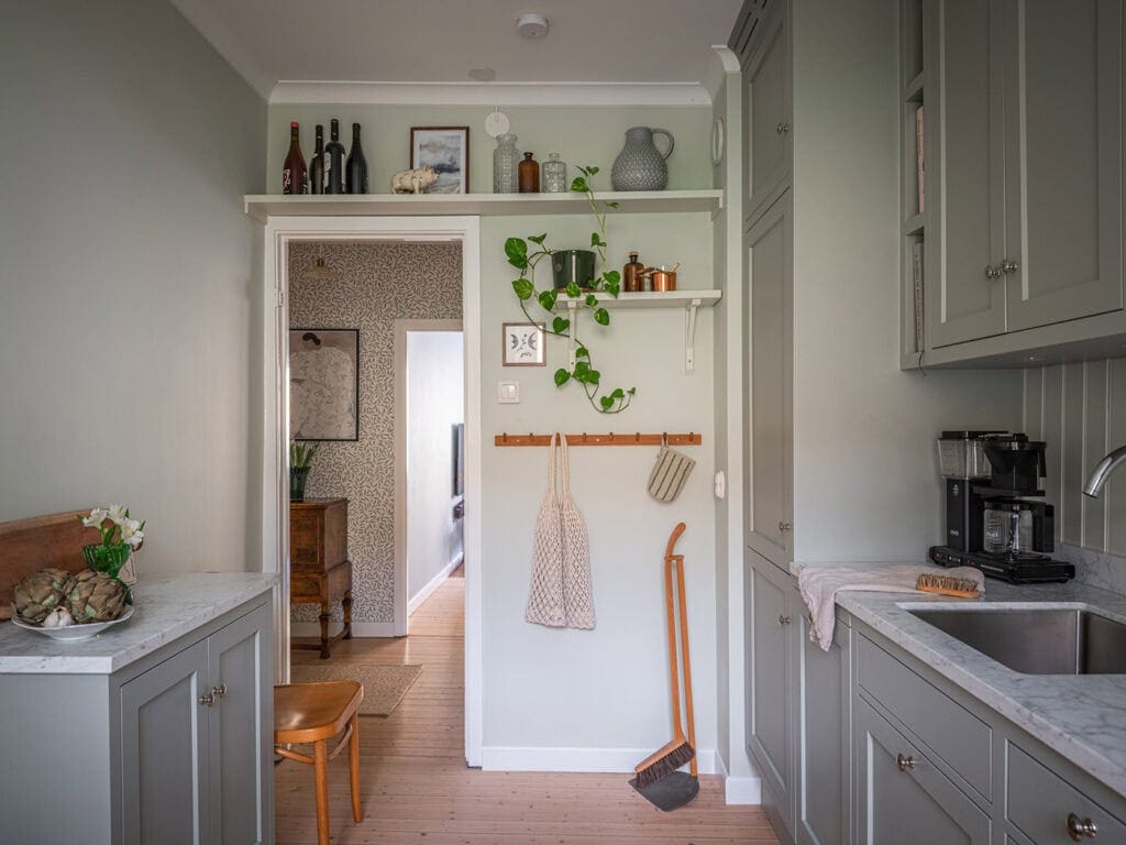 A sage green kitchen with sage green walls and a few natural decor elements