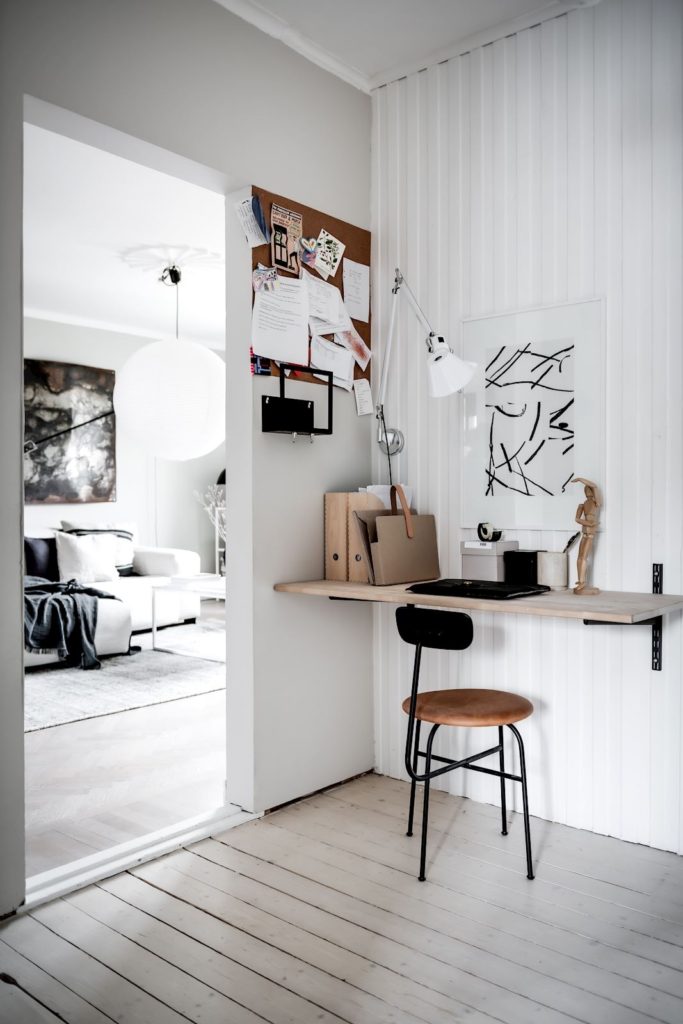 A floating desk with a cork pin board placed in an unused hallway corner