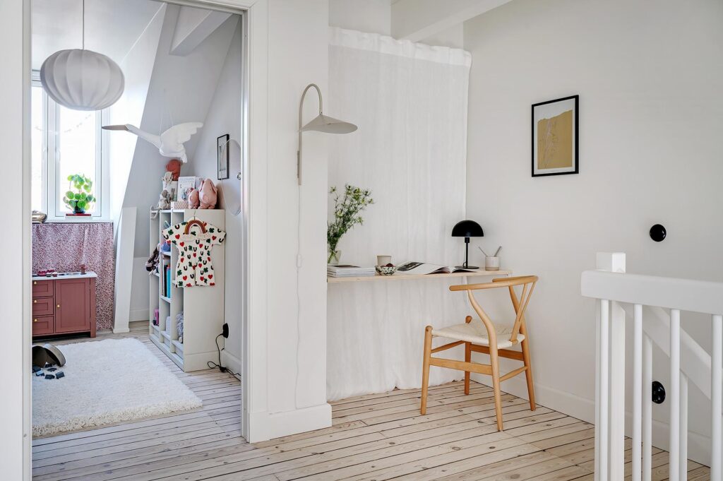 A floating desk with a curtain behind it at the top of the stairs creates a functional workspace