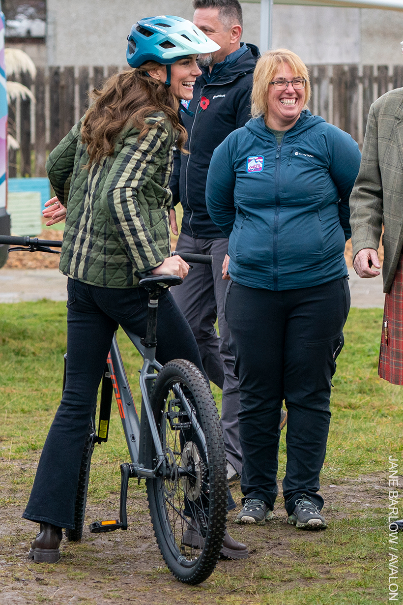 Kate Middleton wearing a pair of cropped skinny flare jeans in dark blue, ankle boots and a check jacket.