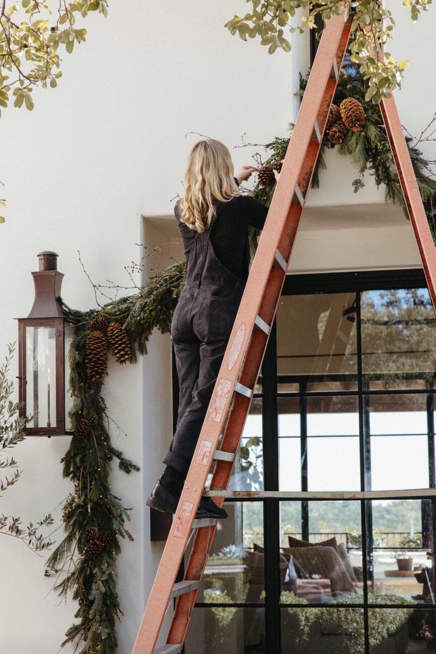 Woman hanging up holiday Christmas garland outside