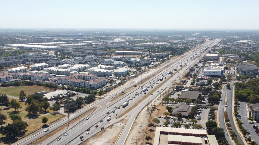 A drone photo above I-35 looking south with a large apartment complex on the east side of the highway. 