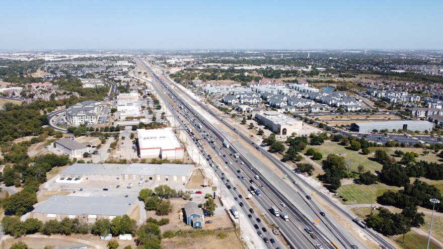 An aerial view of I-35 looking north from above Howard Lane. Apartment buildings are on the east side of the highway. The west side has mostly businesses.  