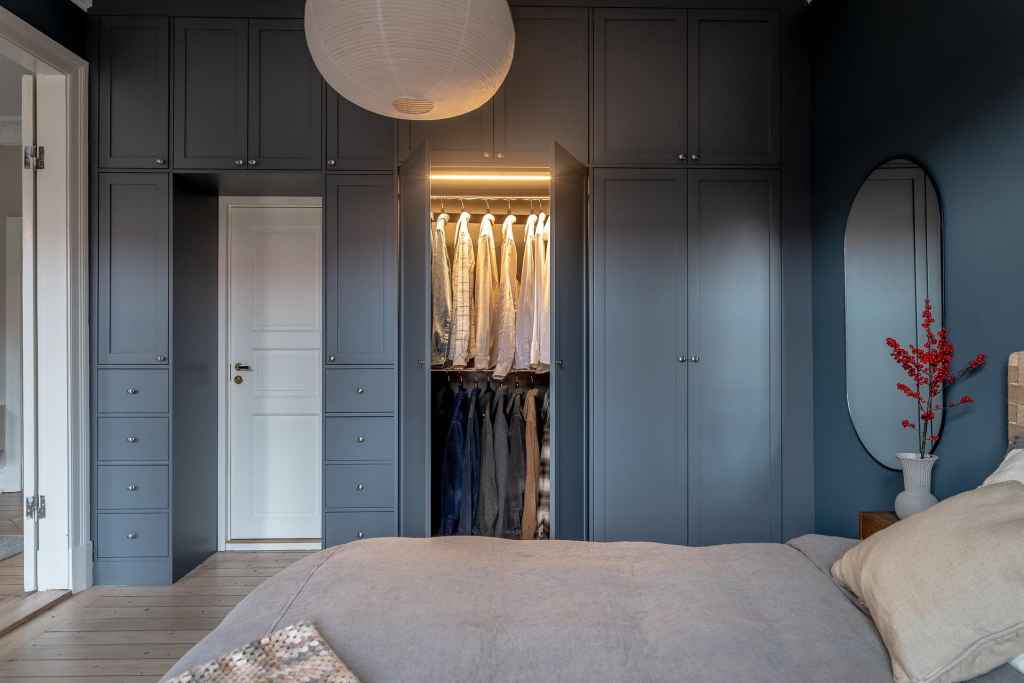 A blue wardrobe with integrated LED lighting going over the door of a blue bedroom