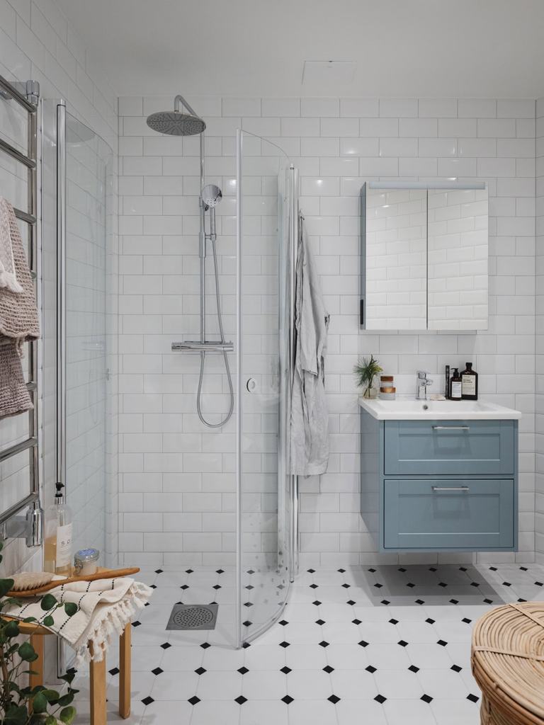 A bathroom with white subway wall tiles, victorian floor tiles, chrome fixtures, and a blue vanity