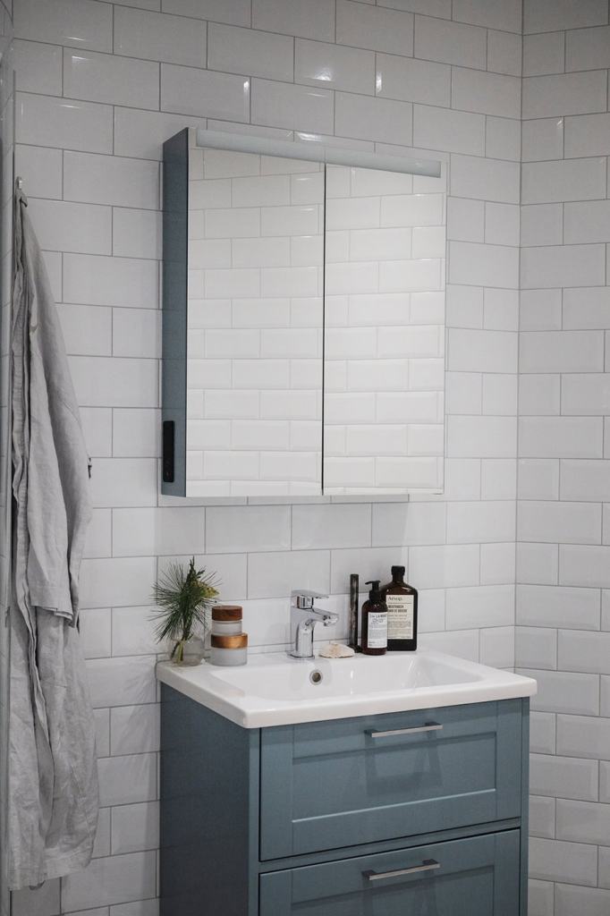 A bathroom with white subway tiles and a blue vanity