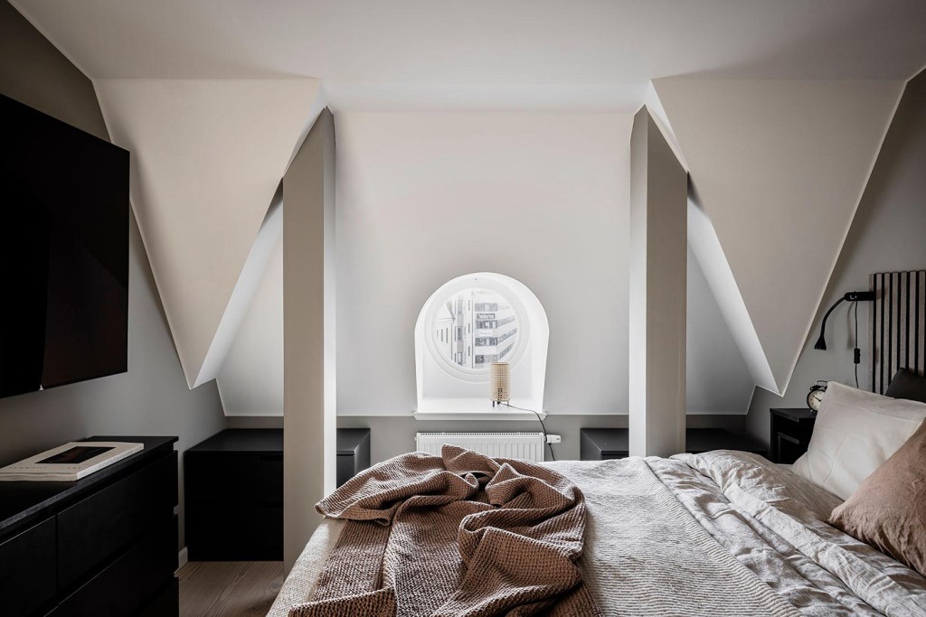 A bedroom with a beige accent wall, black accents and a custom wardrobe