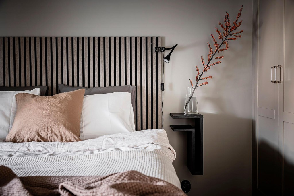 A bedroom with a beige accent wall, black accents and a custom wardrobe