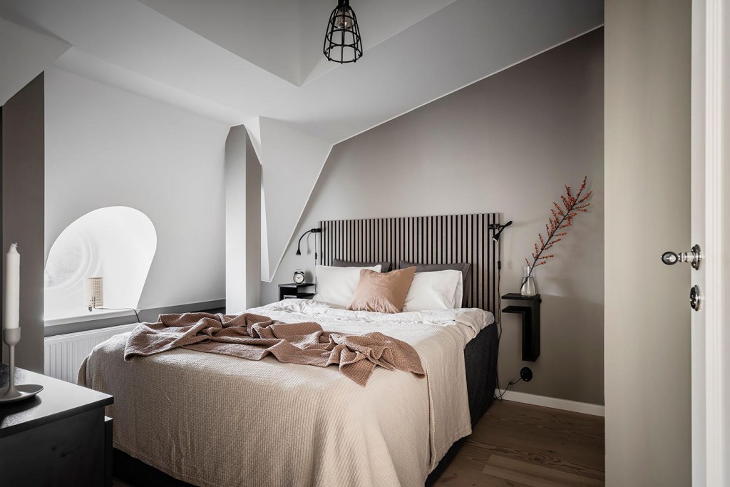 A bedroom with a beige accent wall, black accents and a custom wardrobe