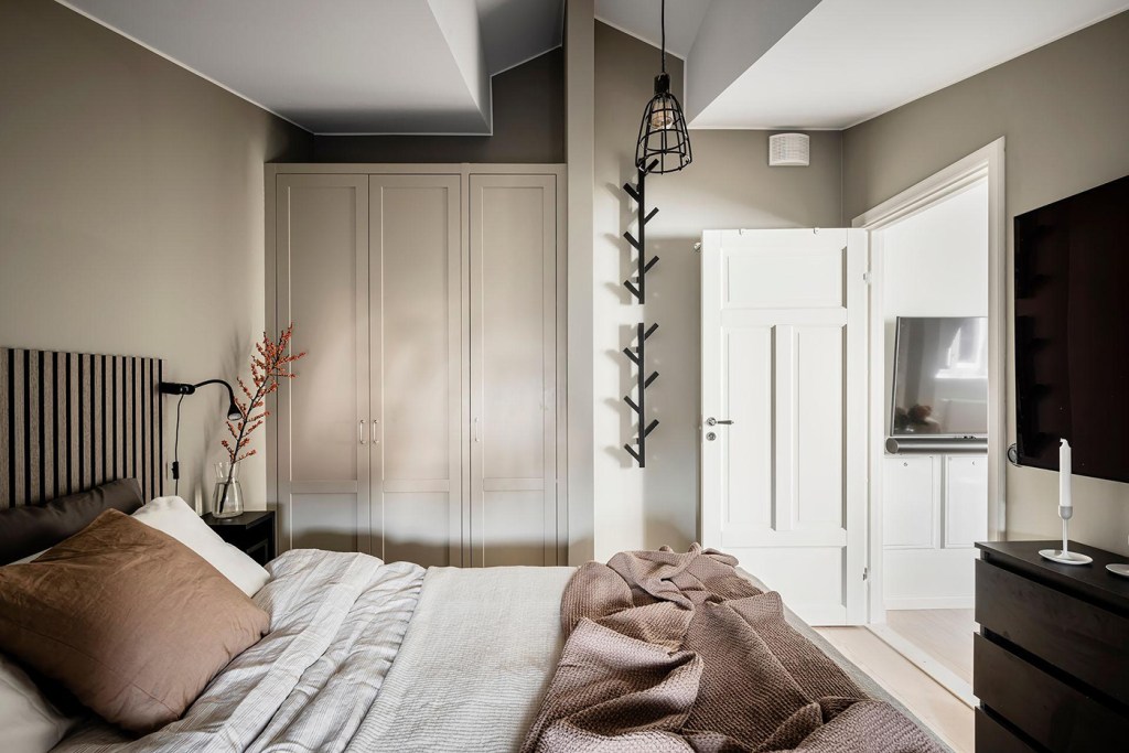 A bedroom with a beige accent wall, black accents and a custom wardrobe