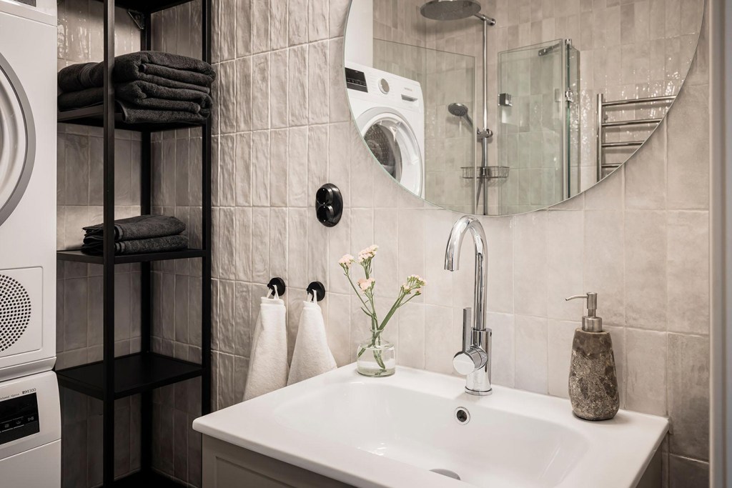 A modern bathroom with beige tiles and black accents