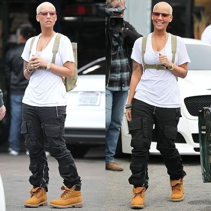 Amber Rose embraces utilitarian style with classic Timberland boots, black cargo pants, a crisp white tee, and an army-inspired backpack for a bold, practical look