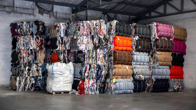 Bales of used clothes are stacked in a warehouse.