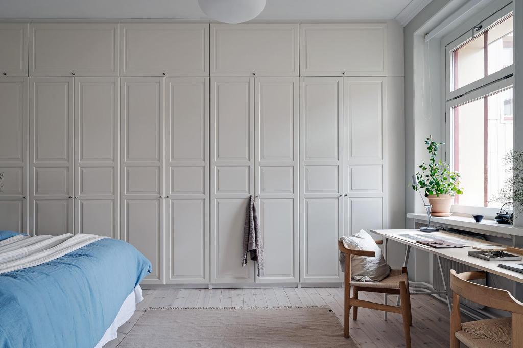 A floor-to-ceiling wardrobe spreading across the entire wall of a light grey bedroom