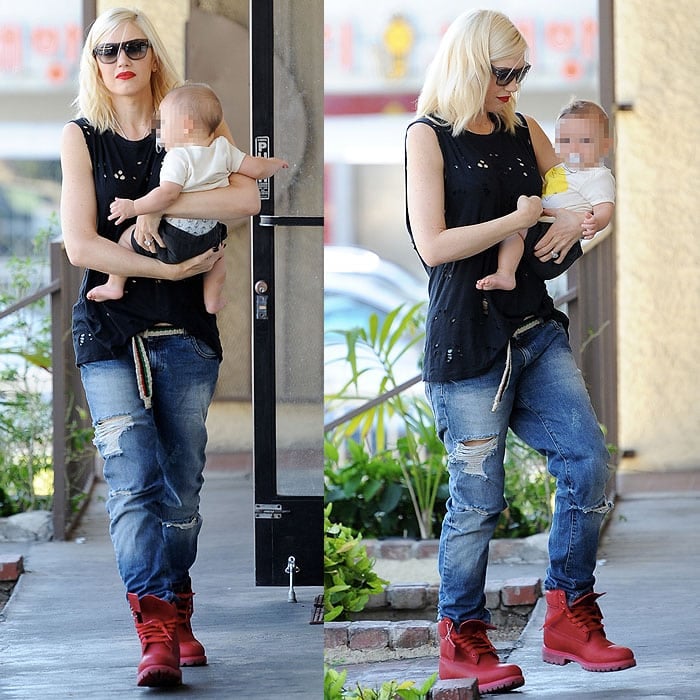 Gwen Stefani keeps it effortlessly edgy in bold red Timberland boots, distressed boyfriend jeans, and a black sleeveless top while out and about with her baby