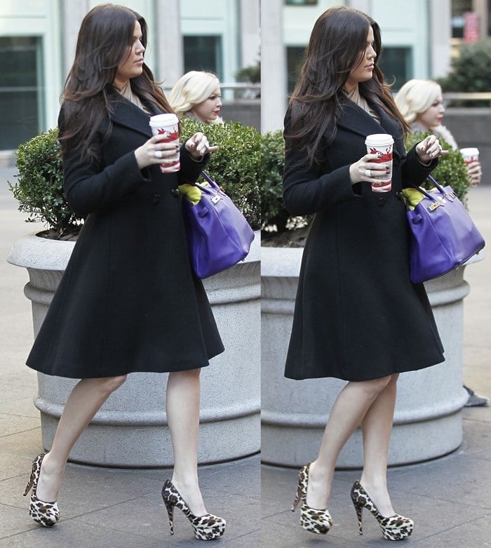 Khloé Kardashian elevates her classic black coat with bold leopard-print pumps and a vibrant purple handbag, effortlessly combining elegance with a pop of personality