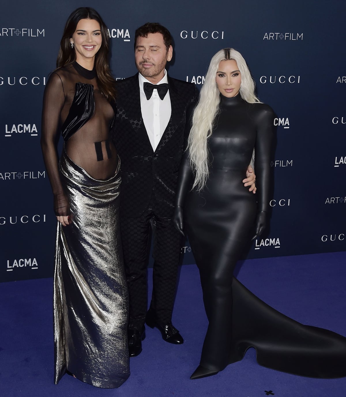 Kendall Jenner turns heads in a sheer black-and-silver gown, while Kim Kardashian opts for a sleek black latex look as they pose with Italian fashion designer Manuele Malenotti at the 2022 LACMA Art + Film Gala