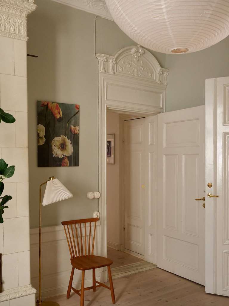 A bedroom with grey walls with green undertones, beige textiles and custom wardrobes flanking the bed