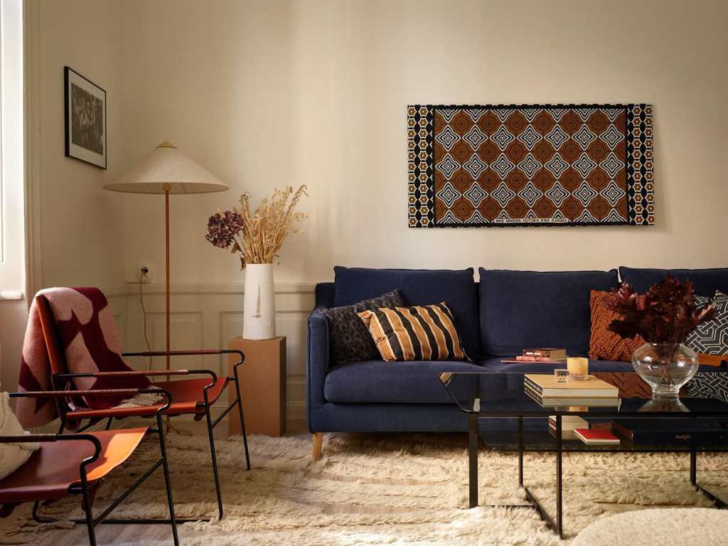 A white living room with a blue sofa and red armchairs