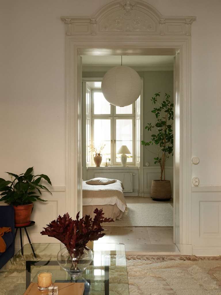 A bedroom with grey walls with green undertones, beige textiles and custom wardrobes flanking the bed