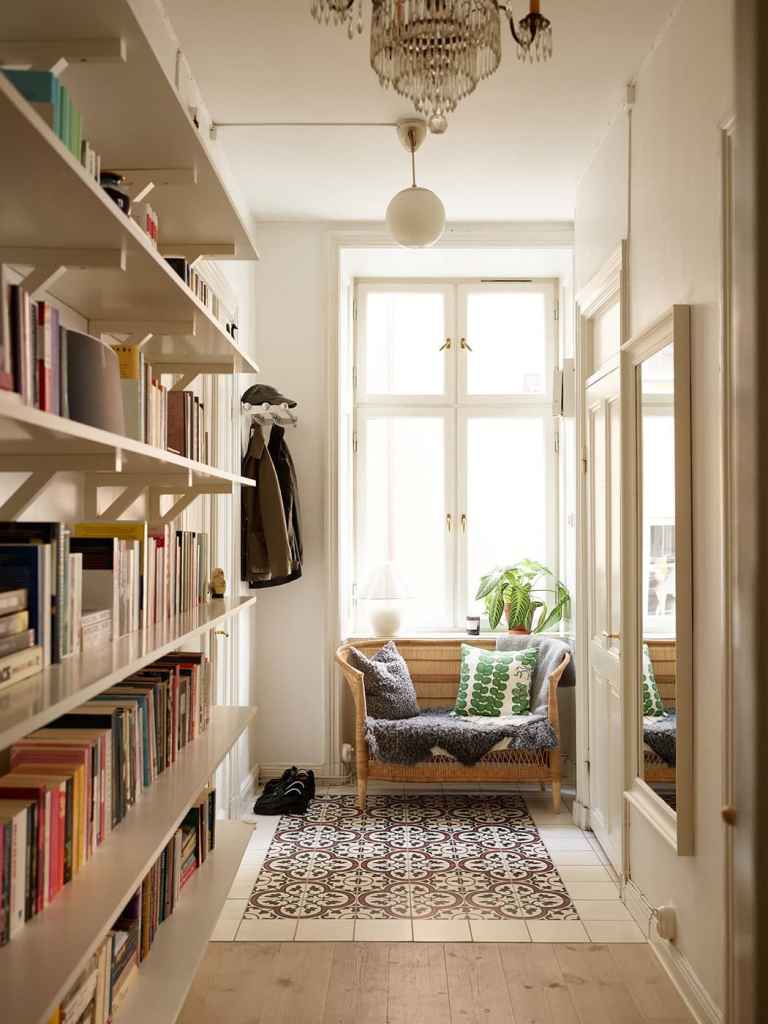 A hallway with a book shelf and a small seating bench