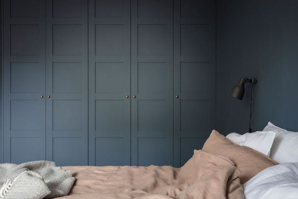 A dark blue wall-to-wall closet matches the walls of a dark blue bedroom